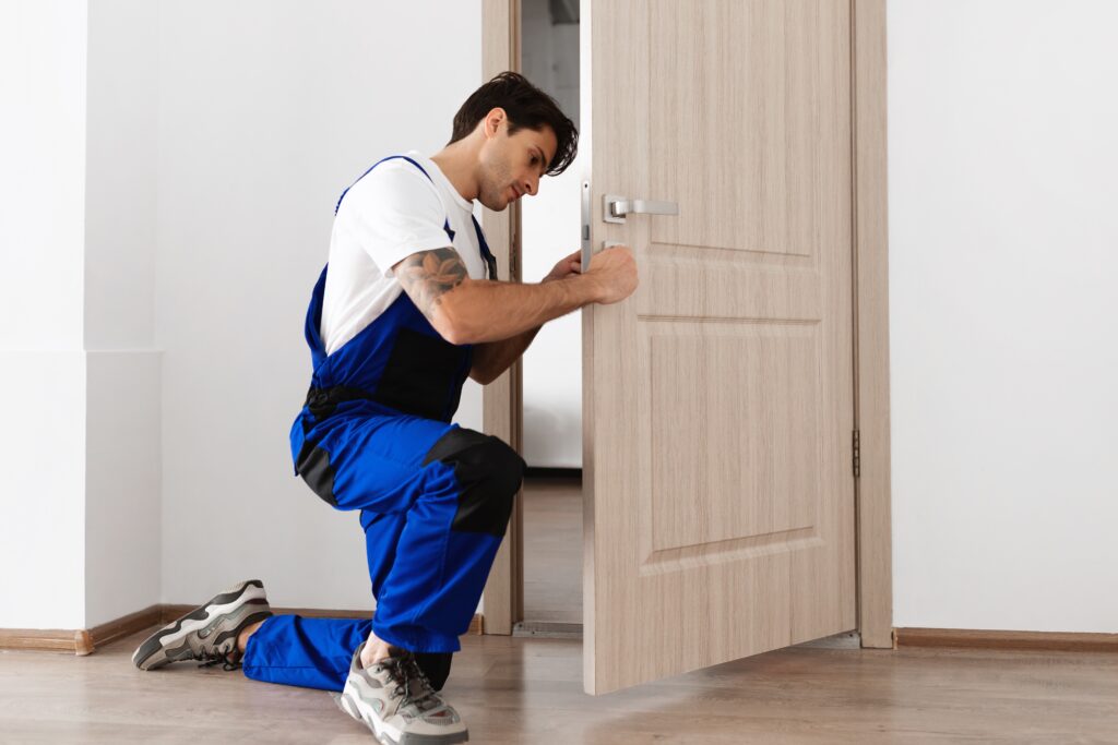 Guy in blue overalls fitting door hardware