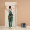 Guy in green overalls measuring a door