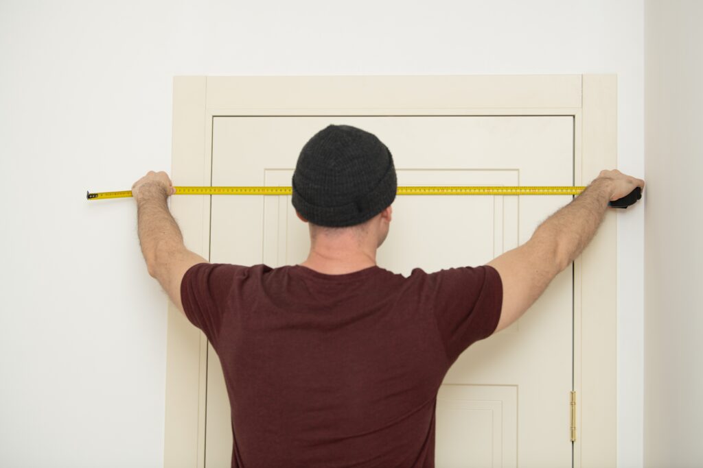 Man With Hat Measures Door Frame