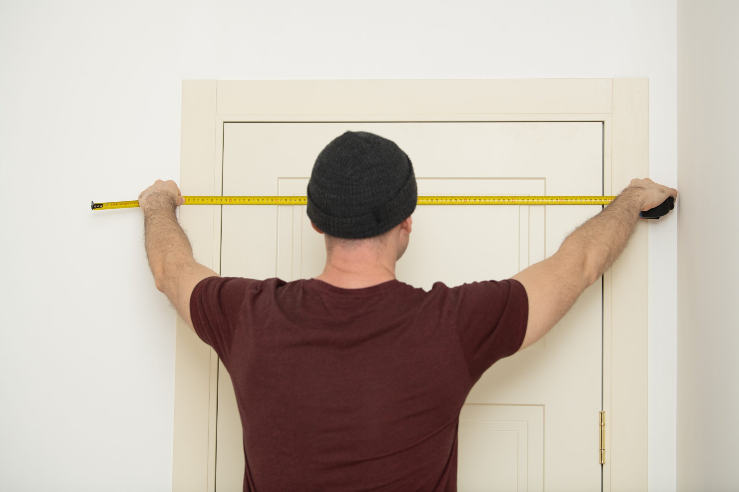 Man With Hat Measures Door Frame